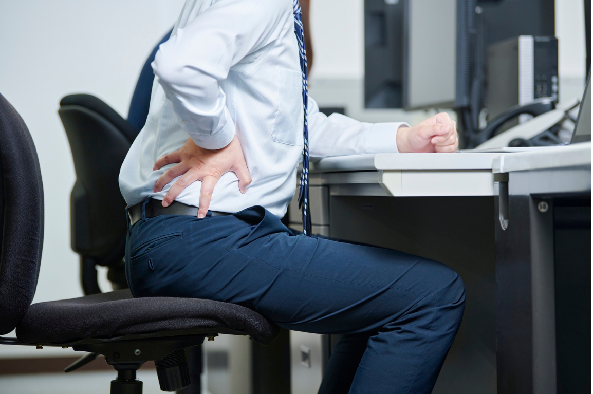 デスクワークで腰を押さえる従業員のイラスト
