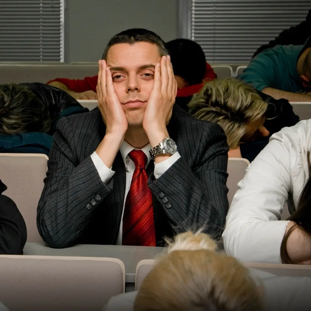 製造業の安全大会で、一方通行の講演に退屈して眠そうにしている従業員たち